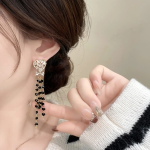 Detailed view of long tassel earrings featuring black heart beads and crystal heart studs