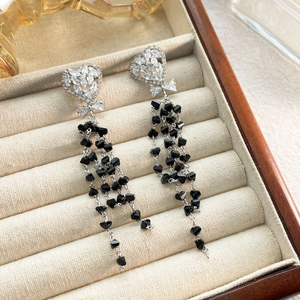 Detail of silver heart earrings with bow knots and black crystal bead tassels