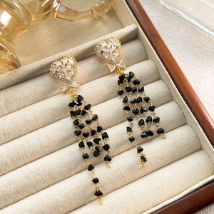 Detailed close-up of heart studs with long gold tassels and black faceted beads