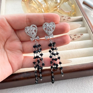 Detail of heart stud earrings with black crystal tassels and zircon bow accents