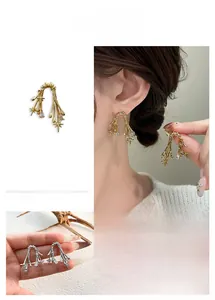 Detailed view of thorn branch earrings with star charms and zircon droplets in gold finish