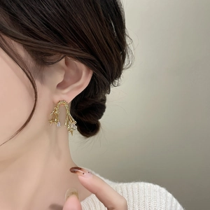 Detail of 18K gold plated thorn earring with zircon stars and teardrop pendant on model