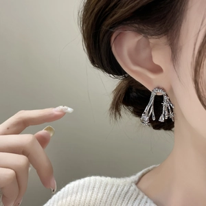 Thorn-inspired silver tassel earrings with zircons shown on a female model with soft lighting