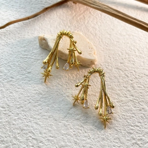 Detailed shot of gold branch earrings with star accents and pear-shaped zircon pendants