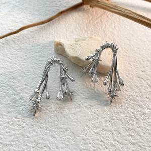 Detailed view of silver thorn branch earrings with star accents and zircon stones