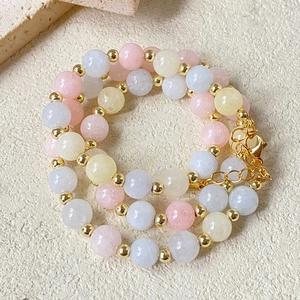 Detail of colorful beaded necklace with pastel stones and gold spacers on beige texture
