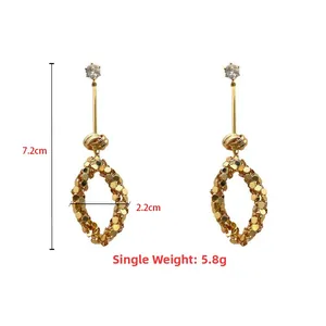 Dettaglio di orecchini lunghi dorati con paillettes e dimensioni di 7,2 cm per 2,2 cm