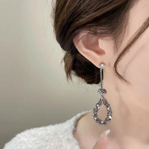 Dettaglio di orecchini pendenti argento con perni in zircone, nodi e gocce con paillettes