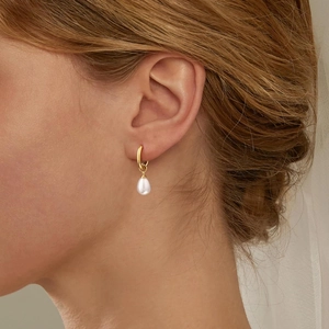 Elegant pearl drop earrings with gold hoops worn by a model for a sophisticated look