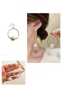 Macro shot of 18K gold and silver hoop earrings with large white pearl pendants