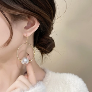 Close-up of model wearing retro gold hoop earrings with a large round pearl drop