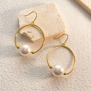 Detailed macro view of gold-plated hoop earrings with large round white pearls
