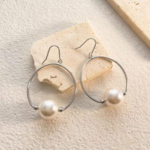 Detailed view of silver hoop earrings with large white pearls and 18K gold plating finish
