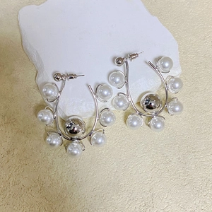 Detail of silver U-shaped hoop earrings featuring polished metal and inlaid white pearls
