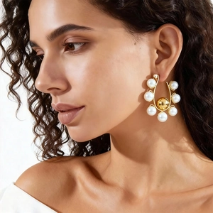Elegant U-shaped gold hoop earrings with white pearls and large center bead on model