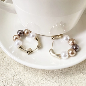 Détail macro de boucles d'oreilles en U plaquées or avec perles blanches et lavande