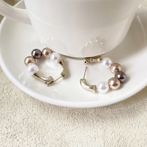 Boucles d'oreilles en perles plaquées or en forme de U sur une soucoupe en porcelaine