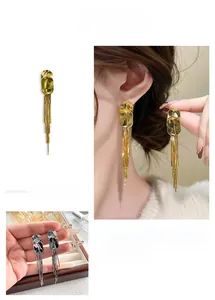 Detailed view of long metal tassel earrings in gold and silver with geometric studs