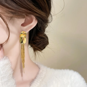 Close-up of elegant long gold tassel earrings with polished metallic fringe and stud detail