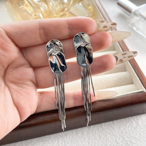 Close-up of long silver tassel earrings with irregular hammered oval metal plates