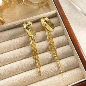 Detail of long gold tassel earrings with sleek snake chains in a velvet jewelry box