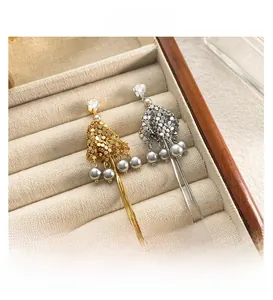 Dettaglio di orecchini a nappa in oro e argento con paillettes e perle in scatola velluto