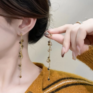 Elegant gold tassel earrings with brown natural stones and sparkling zircons on model