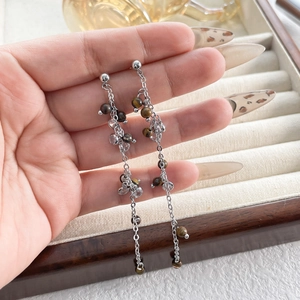 Close-up of elegant long tassel earrings featuring tiger eye stones and silver chain tassels