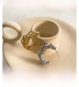 Dettaglio macro di orecchini a C placcati in oro 18k e argento con zirconi brillanti