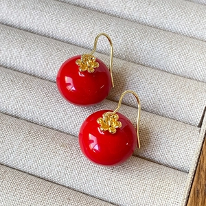 Retro red sphere drop earrings with golden flower accents on a beige velvet jewelry box
