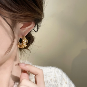 Dettaglio di orecchini a cerchio traforati placcati oro 18k con cristalli su modella