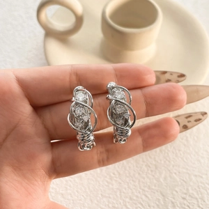 Dettaglio degli orecchini a perno in argento intrecciato con pietre di zircone lucide