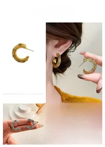 Detailed macro view of C-shaped earrings featuring a refined mesh texture in gold and silver