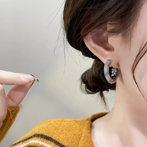 Silver C-shaped hoop earrings with shimmering mesh texture on female model ear
