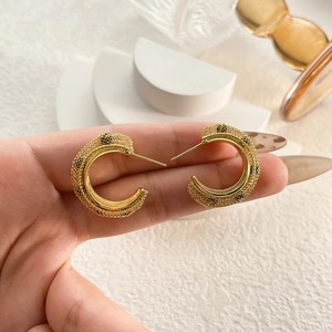 Elegant gold C-shaped mesh hoop earrings with intricate metallic woven texture and studs