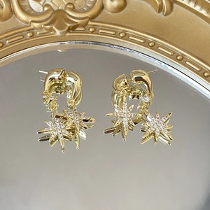 Detailed close-up of gold eight-pointed star earrings with shimmering cubic zirconia