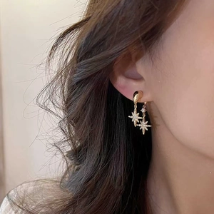 Close-up of model wearing gold starburst earrings with pavé set cubic zirconia crystals