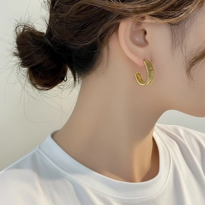 Pendientes de aro bañados en oro de 18K con textura tejida mostrados en modelo