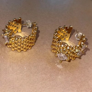 Detail view of gold C-shaped earrings with textured weave and cubic zirconia stones