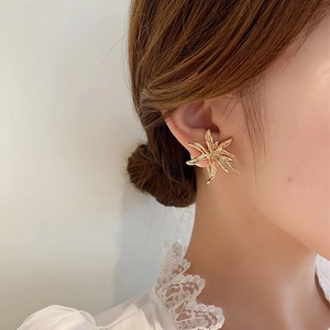 Close-up of elegant gold oversized flower earrings worn by a model in lace attire