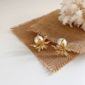 Detailed macro shot of gold flower-shaped earrings featuring large white round pearls