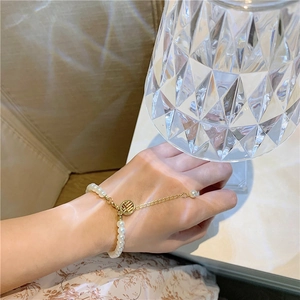 Elegant pearl bracelet with golden Xi character pendant on a female model's wrist