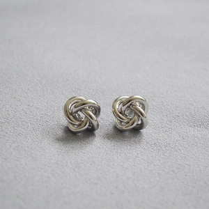 Macro detail of polished silver love knot earrings with mirror-like metallic finish