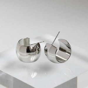 Macro shot of silver chunky C-shaped metal hoop earrings with high-polish mirror finish