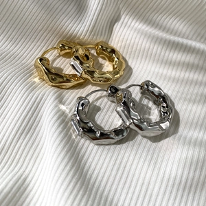 Macro detail of molten texture earrings with rectangular zircon on white silk