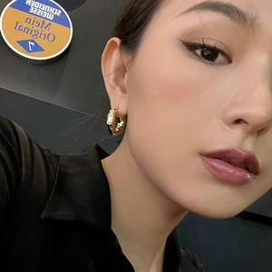 Detail of chunky gold hoop earring with a rectangular crystal stud on a model