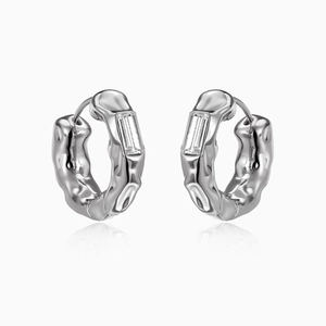 Detail of silver lava textured earrings with rectangular clear gemstones on white background