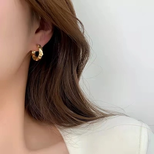Minimalist geometric gold hoop earrings with textured metal finish shown on model