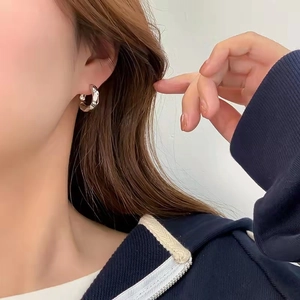 Minimalist silver geometric hoop earrings with textured hammered finish on a model