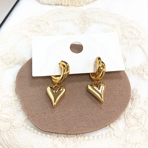 Vue détaillée de boucles d'oreilles cœur dorées polies sur un fond de dentelle blanche